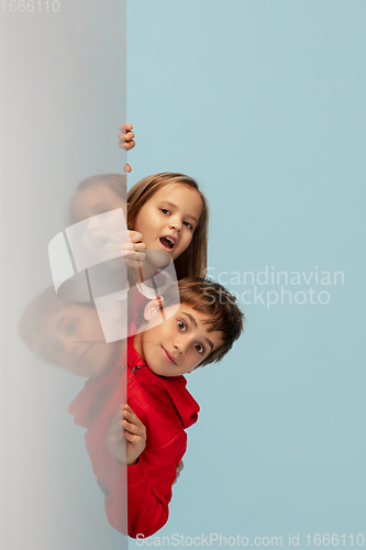 Image of Happy children isolated on blue studio background. Look happy, cheerful, sincere. Copyspace. Childhood, education, emotions concept