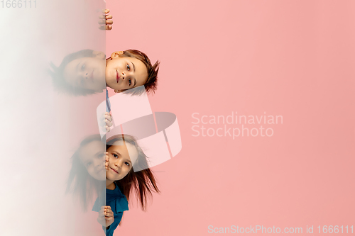 Image of Happy children isolated on coral pink studio background. Look happy, cheerful, sincere. Copyspace. Childhood, education, emotions concept