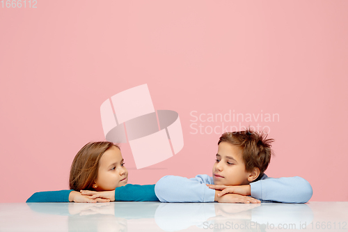 Image of Happy children isolated on coral pink studio background. Look happy, cheerful, sincere. Copyspace. Childhood, education, emotions concept