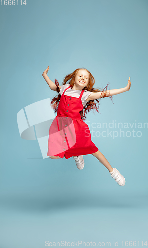 Image of Happy redhair girl isolated on blue studio background. Looks happy, cheerful, sincere. Copyspace. Childhood, education, emotions concept