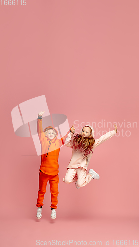 Image of Happy children isolated on coral pink studio background. Look happy, cheerful, sincere. Copyspace. Childhood, education, emotions concept