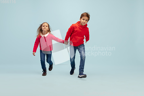 Image of Happy children isolated on blue studio background. Look happy, cheerful, sincere. Copyspace. Childhood, education, emotions concept