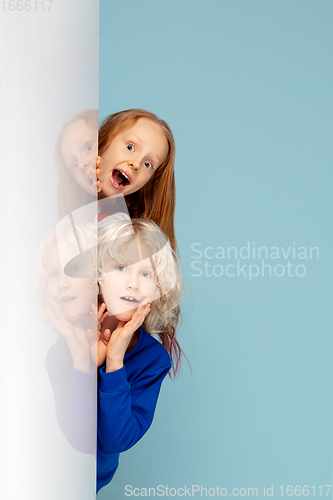 Image of Happy children isolated on blue studio background. Look happy, cheerful, sincere. Copyspace. Childhood, education, emotions concept