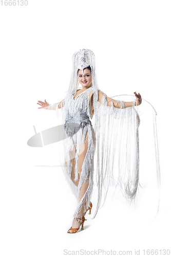 Image of Beautiful young woman in carnival, stylish masquerade costume with feathers dancing on white studio background. Concept of holidays celebration, festive time, fashion