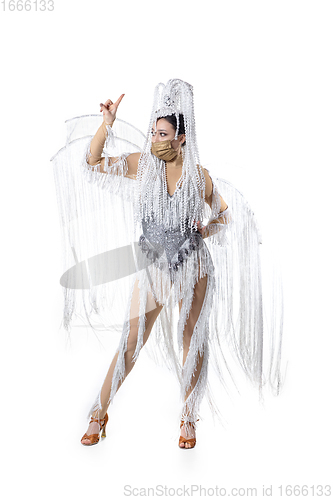 Image of Beautiful young woman in carnival, stylish masquerade costume with feathers dancing on white studio background. Concept of holidays celebration, festive time, fashion