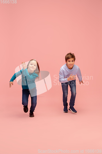 Image of Happy children isolated on coral pink studio background. Look happy, cheerful, sincere. Copyspace. Childhood, education, emotions concept