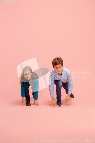 Image of Happy children isolated on coral pink studio background. Look happy, cheerful, sincere. Copyspace. Childhood, education, emotions concept