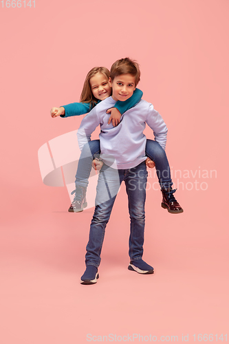 Image of Happy children isolated on coral pink studio background. Look happy, cheerful, sincere. Copyspace. Childhood, education, emotions concept