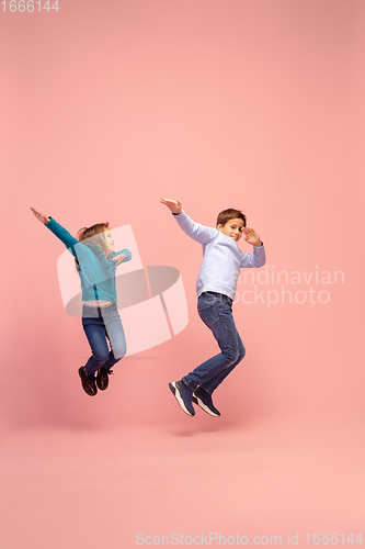 Image of Happy children isolated on coral pink studio background. Look happy, cheerful, sincere. Copyspace. Childhood, education, emotions concept