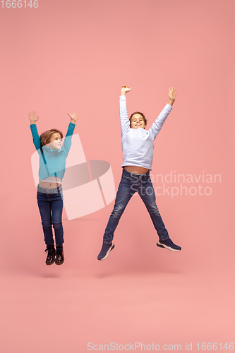 Image of Happy children isolated on coral pink studio background. Look happy, cheerful, sincere. Copyspace. Childhood, education, emotions concept