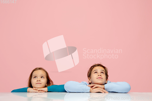 Image of Happy children isolated on coral pink studio background. Look happy, cheerful, sincere. Copyspace. Childhood, education, emotions concept