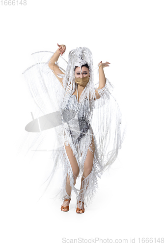 Image of Beautiful young woman in carnival, stylish masquerade costume with feathers dancing on white studio background. Concept of holidays celebration, festive time, fashion