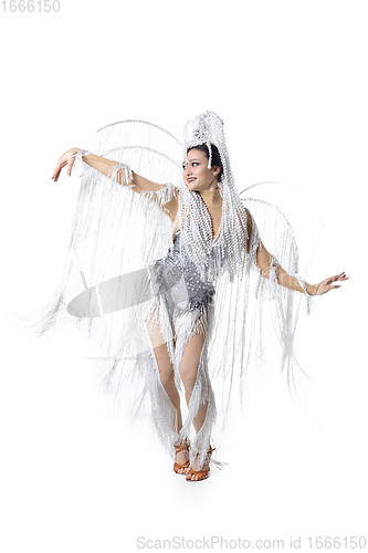 Image of Beautiful young woman in carnival, stylish masquerade costume with feathers dancing on white studio background. Concept of holidays celebration, festive time, fashion