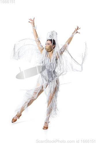 Image of Beautiful young woman in carnival, stylish masquerade costume with feathers dancing on white studio background. Concept of holidays celebration, festive time, fashion