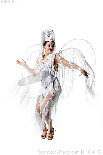Image of Beautiful young woman in carnival, stylish masquerade costume with feathers dancing on white studio background. Concept of holidays celebration, festive time, fashion
