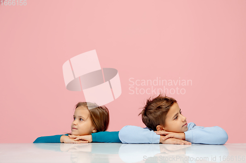 Image of Happy children isolated on coral pink studio background. Look happy, cheerful, sincere. Copyspace. Childhood, education, emotions concept