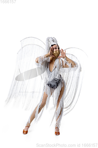 Image of Beautiful young woman in carnival, stylish masquerade costume with feathers dancing on white studio background. Concept of holidays celebration, festive time, fashion