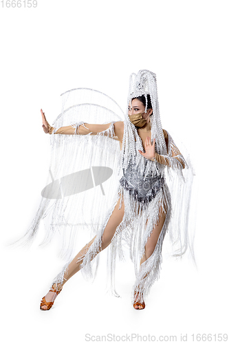 Image of Beautiful young woman in carnival, stylish masquerade costume with feathers dancing on white studio background. Concept of holidays celebration, festive time, fashion