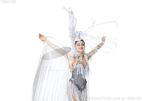 Image of Beautiful young woman in carnival, stylish masquerade costume with feathers dancing on white studio background. Concept of holidays celebration, festive time, fashion