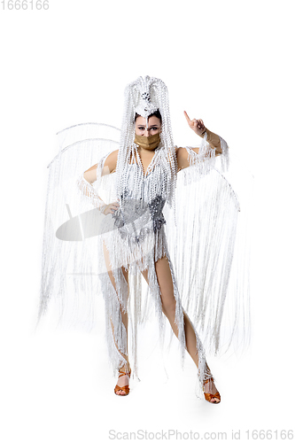 Image of Beautiful young woman in carnival, stylish masquerade costume with feathers dancing on white studio background. Concept of holidays celebration, festive time, fashion