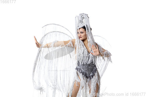 Image of Beautiful young woman in carnival, stylish masquerade costume with feathers dancing on white studio background. Concept of holidays celebration, festive time, fashion