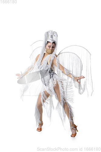 Image of Beautiful young woman in carnival, stylish masquerade costume with feathers dancing on white studio background. Concept of holidays celebration, festive time, fashion