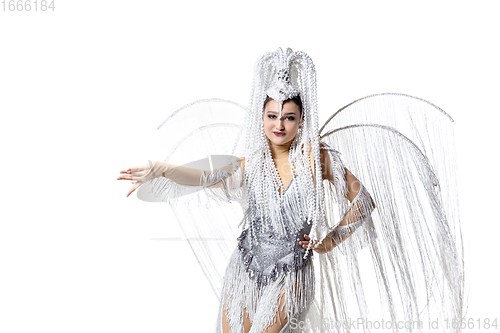 Image of Beautiful young woman in carnival, stylish masquerade costume with feathers dancing on white studio background. Concept of holidays celebration, festive time, fashion