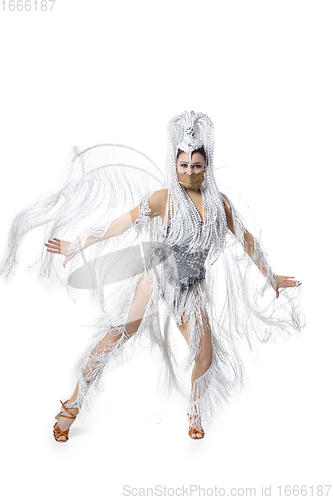 Image of Beautiful young woman in carnival, stylish masquerade costume with feathers dancing on white studio background. Concept of holidays celebration, festive time, fashion