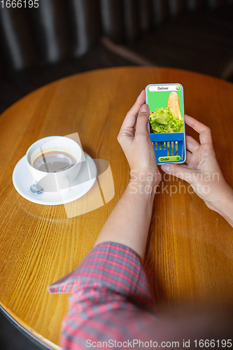 Image of Close up hands holding smartphone with food delivery service on the screen. Staying safe during lockdown. Modern tech and healthcare