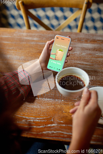 Image of Close up hands holding smartphone with food delivery service on the screen. Staying safe during lockdown. Modern tech and healthcare