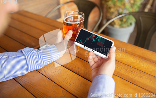Image of Close up hands holding smartphone with trading information graphs on the screen. Business, finance. Modern tech and work.