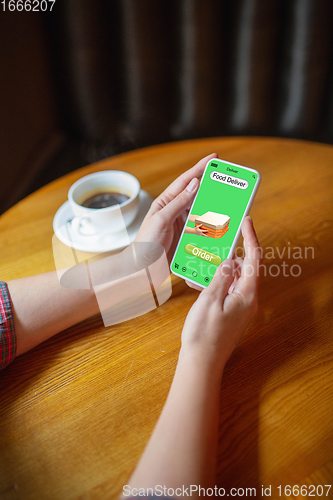 Image of Close up hands holding smartphone with food delivery service on the screen. Staying safe during lockdown. Modern tech and healthcare