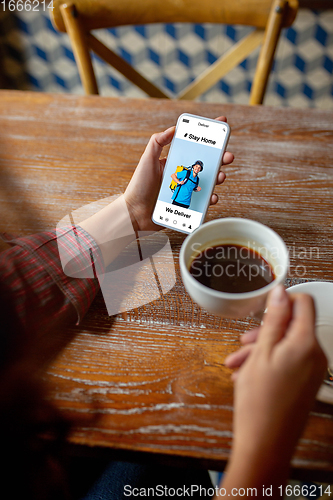 Image of Close up hands holding smartphone with food delivery service on the screen. Staying safe during lockdown. Modern tech and healthcare