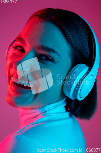 Image of Caucasian woman\'s portrait isolated on pink studio background in multicolored neon light