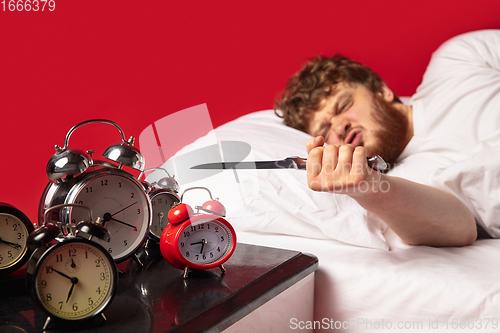 Image of Man wakes up and he\'s mad at clock ringing, switches it off with kitchen knife