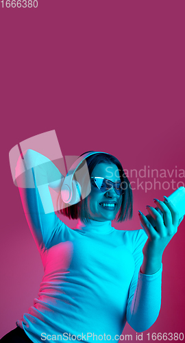 Image of Caucasian woman\'s portrait isolated on pink studio background in multicolored neon light