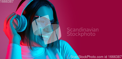 Image of Caucasian woman\'s portrait isolated on pink studio background in multicolored neon light