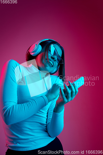 Image of Caucasian woman\'s portrait isolated on pink studio background in multicolored neon light