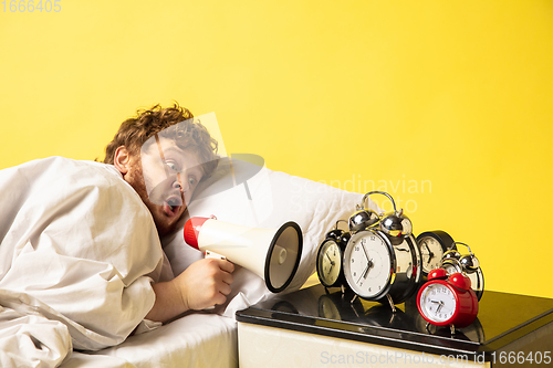 Image of Man wakes up and he\'s mad at clock ringing, switches it off by breaking down with megaphone