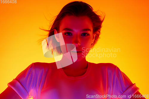 Image of Caucasian woman\'s portrait isolated on orange studio background in multicolored neon light