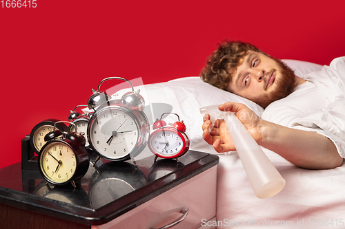 Image of Man wakes up and he\'s mad at clock ringing, switches it off with water spraying