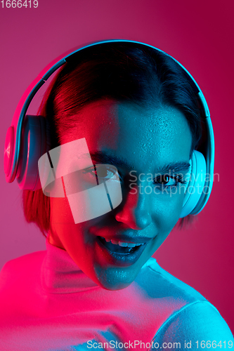 Image of Caucasian woman\'s portrait isolated on pink studio background in multicolored neon light