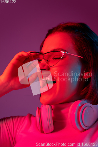 Image of Caucasian woman\'s portrait isolated on pink studio background in multicolored neon light