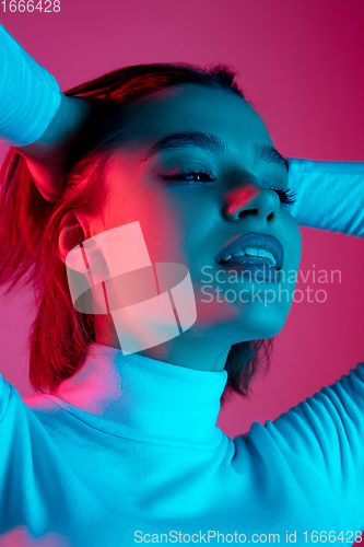 Image of Caucasian woman\'s portrait isolated on pink studio background in multicolored neon light