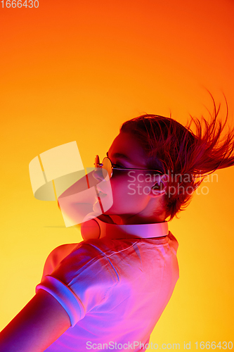 Image of Caucasian woman\'s portrait isolated on orange studio background in multicolored neon light