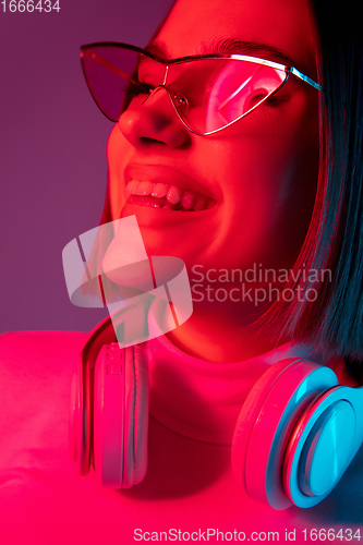 Image of Caucasian woman\'s portrait isolated on pink studio background in multicolored neon light