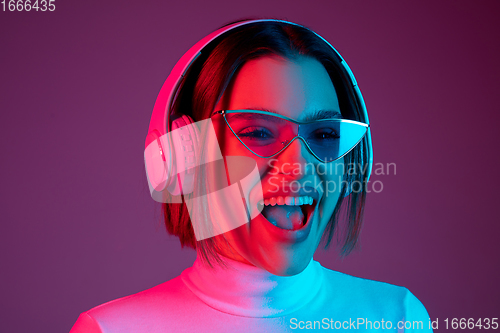 Image of Caucasian woman\'s portrait isolated on pink studio background in multicolored neon light
