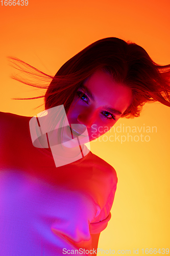 Image of Caucasian woman\'s portrait isolated on orange studio background in multicolored neon light