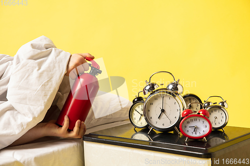 Image of Man wakes up and he\'s mad at clock ringing, switches it off with the extinguisher