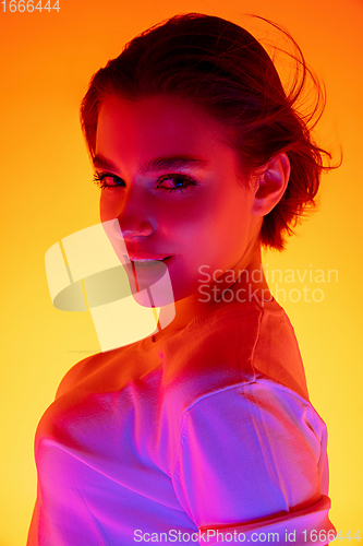 Image of Caucasian woman\'s portrait isolated on orange studio background in multicolored neon light